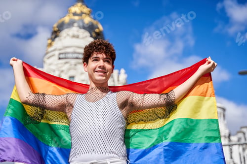 Preview: A man holding a rainbow flag in front of a building