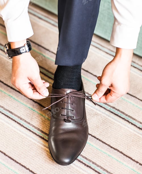 Preview: Close-up young man tying elegant shoes indoors