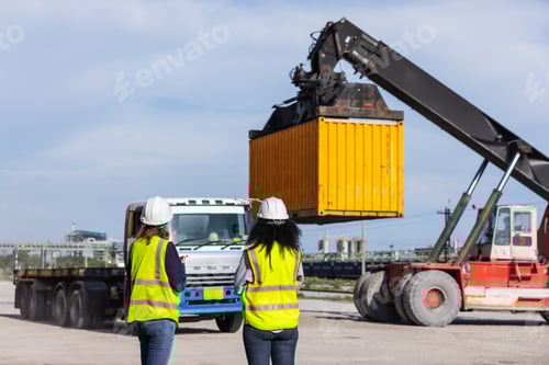 Preview: Two female workers oversee container loading operations at a shipping yard.