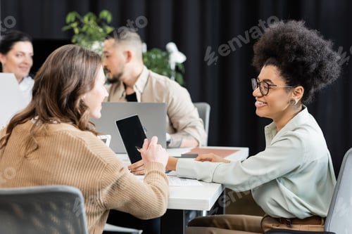 Preview: happy interracial female colleagues talking in modern coworking, project planning and collaboration
