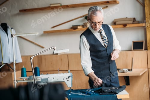 Preview: senior tailor examining cloth at sewing workshop