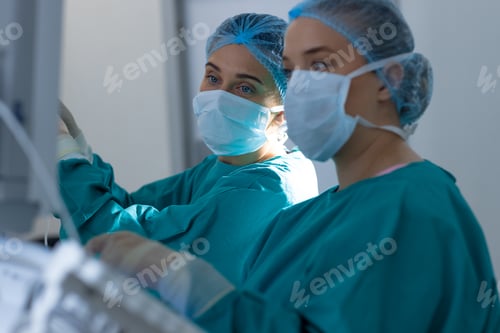 Preview: Diverse surgeons wearing surgical gowns operating on patient in operating theatre at hospital