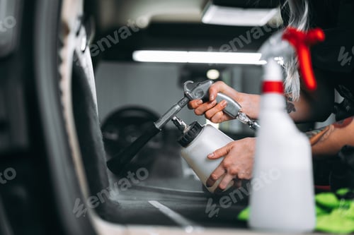 Preview: Woman cleaning car salon with polishing spray in car detailing service