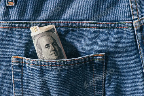 Preview: close up view of roll of dollar banknotes in jeans pocket