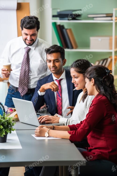 Preview: Indian young businesspeople using laptop in group meeting at desk