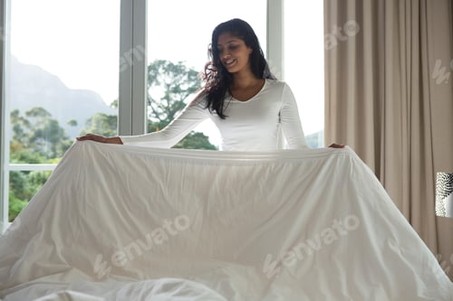 Preview: Young woman making bed