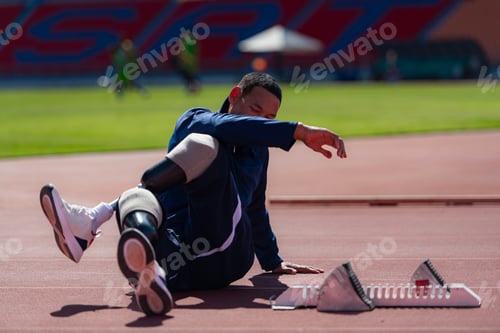 Preview: Disabled athletic man stretching and warming up before running on stadium track