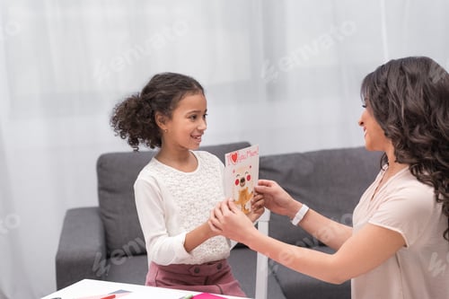 Preview: african american daughter presenting greeting card to mother on mothers day