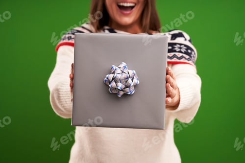 Preview: Adult happy woman with Christmas gift over green background