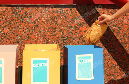 Preview: Woman throwing paper into recycling bin outdoors, closeup