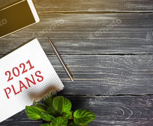 Preview: 2021 Plans concept. Desktop with notebook, phone, pen. Planning goals, plans and tasks.