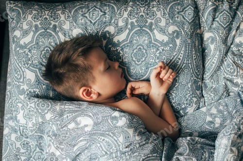 Preview: Cute boy sleeping in bed. Child 6-7 years old smiling, having a good dreams.