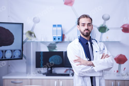 Preview: Attractive bearded doctor with arms crossed looking at the camera in his hospital cabinet