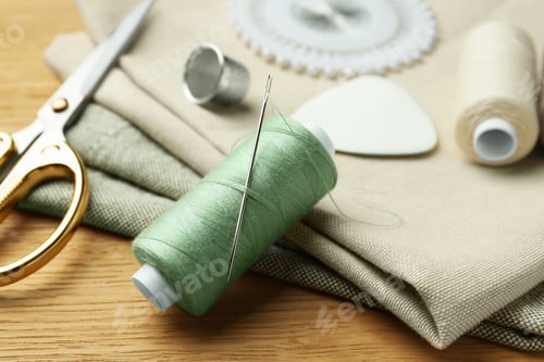 Preview: Spool of thread and sewing tools on wooden table, closeup
