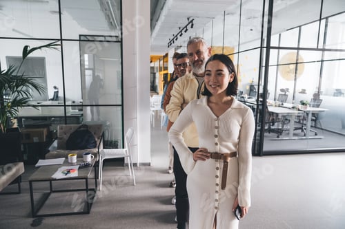 Preview: Team standing in row behind female employee in workplace