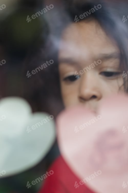 Preview: Child's Face Behind Window with Heart Decorations