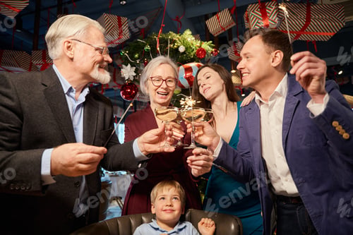 Preview: Family celebrating New Year in restaurant with twinkling lights and champagne