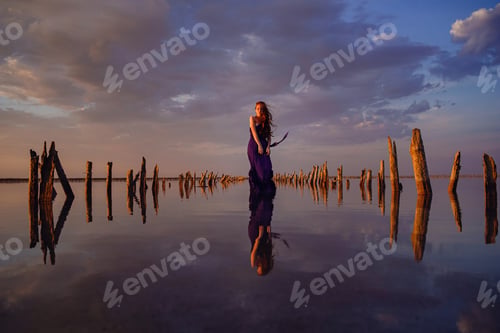 Preview: Elegant woman in silky dress walking by a salt lake.