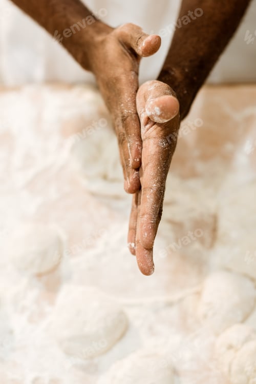 Preview: cropped shot of african american baker preparing dough for pastry and covering hands in flour