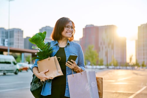 Preview: Woman with shopping paper bags, purchased plant walking outdoor