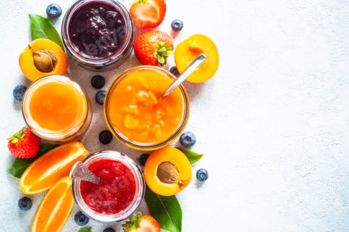 Preview: Homemade jam in glass jars at white table.