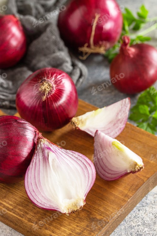 Preview: Purple Onions. Fresh whole purple onions and one sliced onion on a stone countertop.