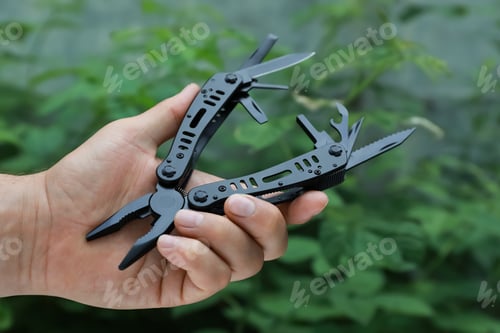 Preview: Man holding compact portable multitool outdoors, closeup