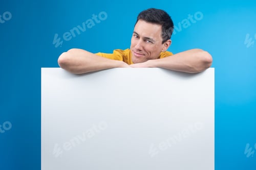 Preview: Cunning man leaning on blank banner in studio