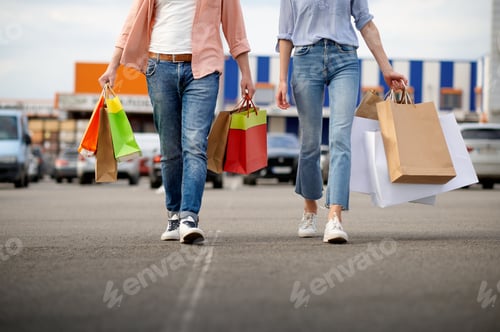 Preview: Man and woman with bags on supermarket car parking