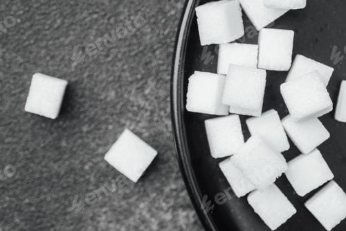 Preview: Sugar cubes arranged on a black plate with some scattered around