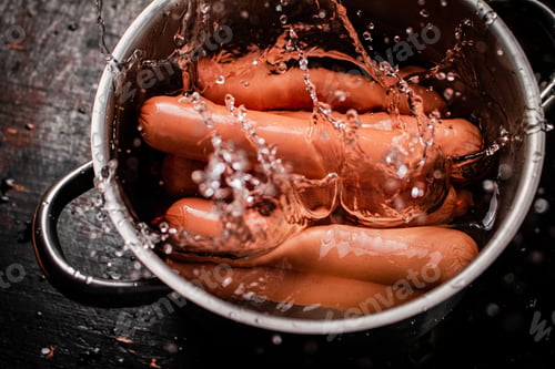 Preview: The sausages boiled fall into a pot with splashes of water.