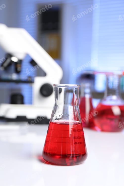 Preview: Laboratory analysis. Glass flask with red liquid and microscope on white table indoors