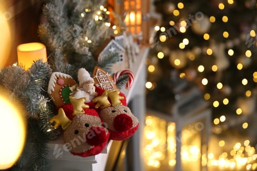 Preview: Sweets in soft slippers on fireplace, space for text. Saint Nicholas Day tradition
