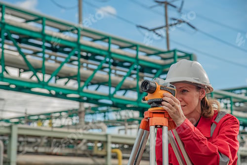 Preview: Woman engineer using theodolite outdoors