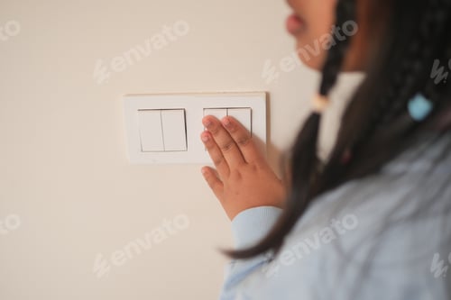 Preview: Child reaching for light switch on a wall in home