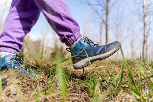 Preview: Selective focus of a hiker's shoes on a grassy field