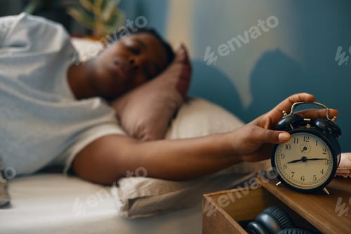 Preview: Man Reaching for Alarm Clock While Lying in Bed