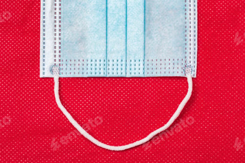 Preview: Fragment of blue medical face mask on background of non-woven fabric bright red color. Concept