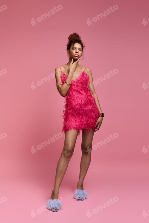 Preview: Stylish young woman poses confidently in vibrant pink outfit against playful backdrop