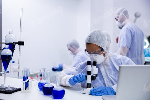 Preview: Female scientist looking at a sample of solution through
