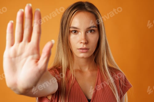 Preview: Confident young blonde woman looking at camera and gesturing 'stop'