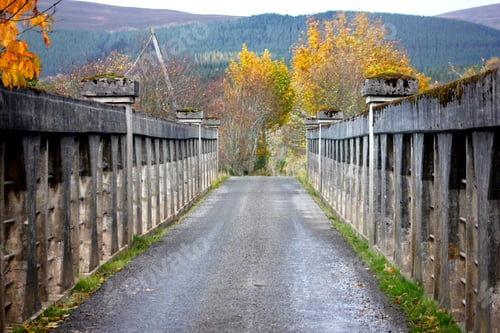 Preview: Looking down tiny stone vehicle bridge in Scotland during autumn with hills in background