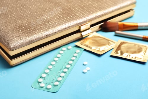 Preview: Birth control pills and condoms near clutch on light blue background. Safe sex concept