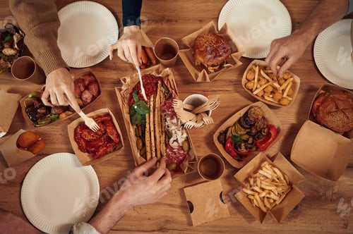 Preview: Top view of table with food on it, hands of the people taking it, eating. Meat, vegetables