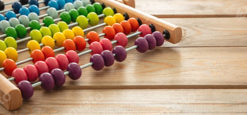Preview: School abacus with colorful beads on wooden desk, close up view