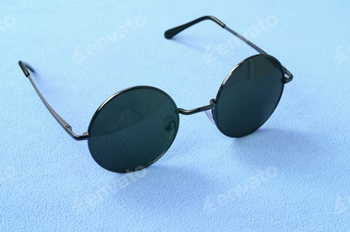 Preview: Stylish black sunglasses with round glasses lies on a blanket made of soft and fluffy light blue