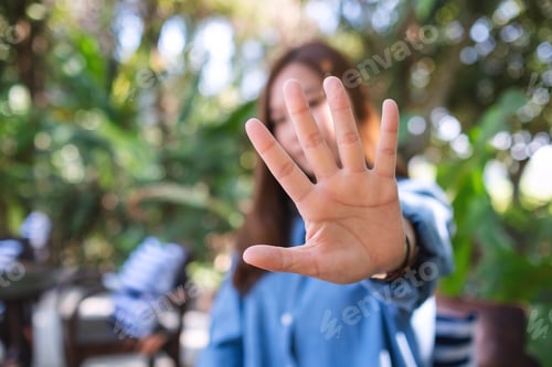 Preview: A young woman outstretched hand and showing stop hand sign