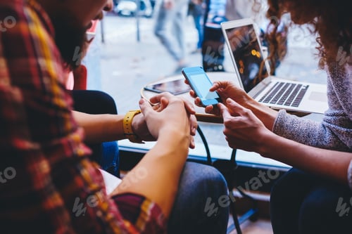 Preview: Crop friends watching smartphone together in cafe