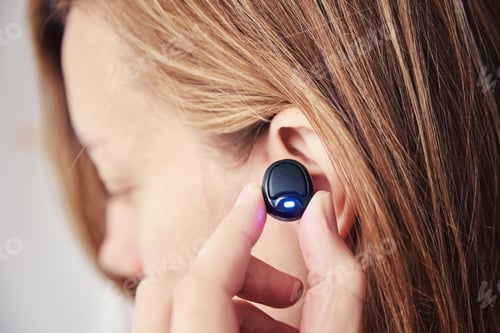 Preview: Woman listening music through wireless earphones
