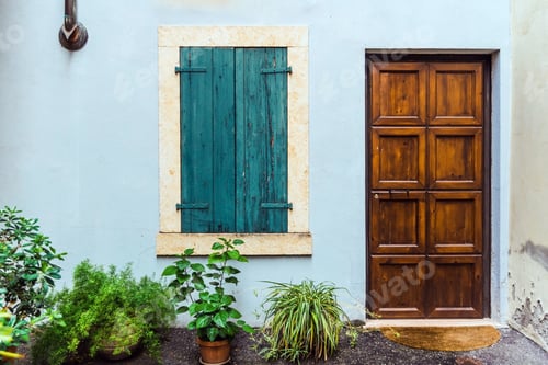 Preview: Closed traditional style wooden door and window on the facade of a house.